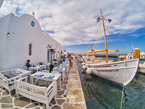 Restaurant in an old church building in Naoussa, Paros, Greece, with seating spreading all the way to the edge of the waterfront, photo by Ivan Kralj