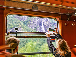 Tourists in the Flam Railway train photographing the waterfall through the window, one of the things to do in Aurland, Norway, photo by Ivan Kralj