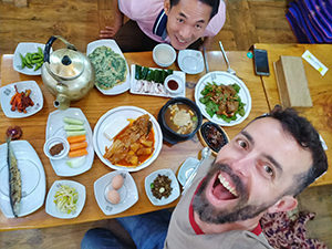 Pipeaway blogger Ivan Kralj and Couchsurfer Yunrok Lee sitting around the table full of various food in the rice wine pub in Jeonju, South Korea, photo by Ivan Kralj