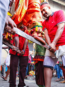 Devotee at Thaipusam Festival 2019 standing barefoot on sabers held in the air by fellow pilgrims, photo by Ivan Kralj