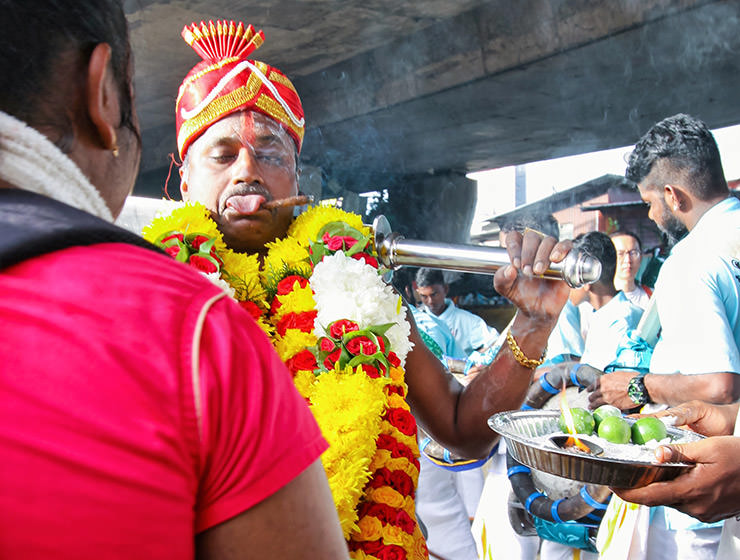 Devotee sticking out his tongue while smoking a cigar at Thaipusam Festival 2019 at Batu Caves, Malaysia, photo by Ivan Kralj