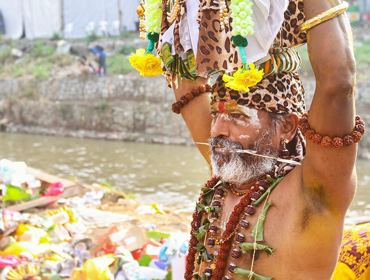 An oldr bearded devotee with pierced cheeks and tongue, carrying a paal kudam at Thaipusam Festival 2019 at Batu Caves, Malaysia, photo by Ivan Kralj