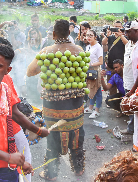 Devotee with dozens of green apples pierced on his back skin at Thaipusam Festival 2019 at Batu Caves, Malaysia, photo by Ivan Kralj