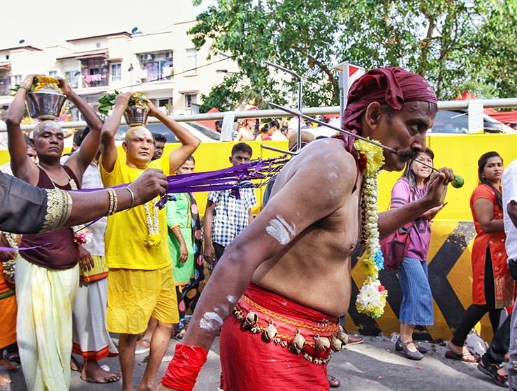 Devotee with pierced cheeks and back skin pulling ropes on the street at Thaipusam Festival 2019 at Batu Caves, Malaysia, photo by Ivan Kralj