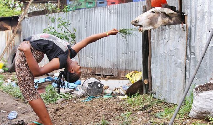Arba Minch Circus contortionist backbending to feed the donkey with grass as a part of fundraising project Circus of Postcards, in Arba Minch, Ethiopia, photo by Ivan Kralj