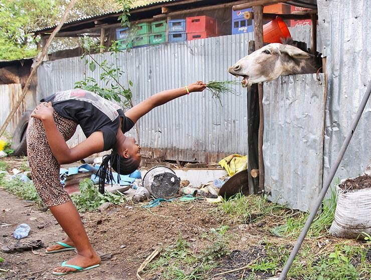 Arba Minch Circus contortionist backbending to feed the donkey with grass as a part of fundraising project Circus of Postcards, in Arba Minch, Ethiopia, photo by Ivan Kralj