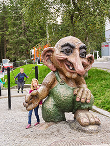 A girl playing around a giant troll sculpture on Mt. Floyen in Bergen, Norway, the wettest place in Europe, photo by Ivan Kralj