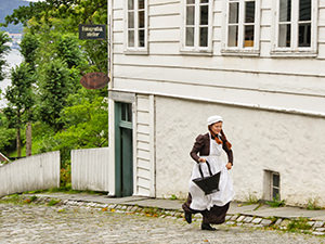 A servant-actress running up the street in the imitation of the 19th-century Bergen at Old Bergen Museum, Norway, photo by Ivan Kralj