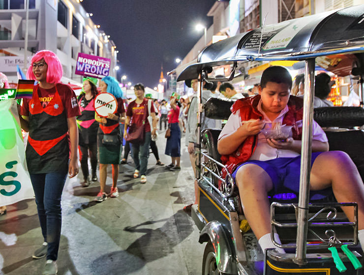 A boy eating his noodles in a tuk-tuk, right next to the Chiang Mai Pride, gay parade in Chiang Mai, Thailand, photo by Ivan Kralj