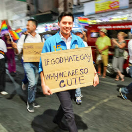 Participant with placard "If God hates gays, why are we wo cute", walking at Chiang Mai Pride, gay parade in Chiang Mai, Thailand, photo by Ivan Kralj