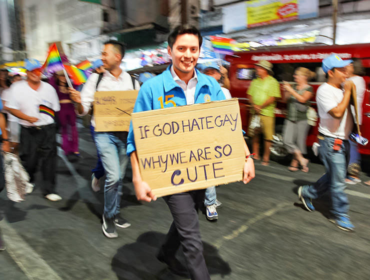Participant with placard "If God hates gays, why are we wo cute", walking at Chiang Mai Pride, gay parade in Chiang Mai, Thailand, photo by Ivan Kralj