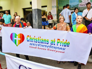 A priest and other participants with a sign "Christians at Pride: God loves everyone", posing at Chiang Mai Pride, gay parade in Chiang Mai, Thailand, photo by Ivan Kralj