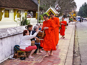 Tourists offer sticky rice to the Buddhist monks passing through the streets of Luang Prabang, Laos, during the alms-giving ceremony or tak bat, photo by Ivan Kralj