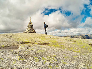 Pipeaway blogger Ivan Kralj standing in front of the cairn structure on Mount Kjerag, Lysefjord, one of the best hikes in Norway, photo by Ivan Kralj