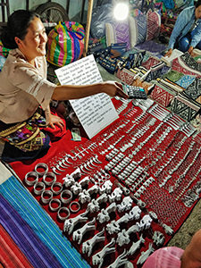 The smiling vendor of the bombshell-made jewelry showing the price on the calculator to a customer on Luang Prabang Night market; visiting the Night market is considered to be one of the best things to do in Luang Prabang, Laos, photo by Ivan Kralj