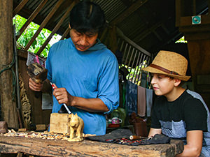 Mr. Lon, the wood carving master, showing the secrets of his trade to a boy attending the Backstreet Academy class session, one of the best things to do in Luang Prabang, Laos, photo by Ivan Kralj