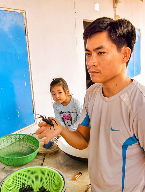 Experience host Ratana Ouch showing the tarantula spider, while his curious 3-year-old daughter lurks what's going on at Backstreet Academy's Fear Factor Challenge cooking class in Siem Reap, Cambodia, a country where they love eating insects, photo by Ivan Kralj