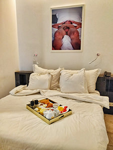 Breakfast in bed with a photograph of a nude man above the bed, in Arthur & Paul hotel in Phnom Penh, photo by Ivan Kralj