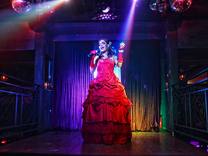 Drag queen performer lip syncing in a red gown on the stage of Barcode, in Siem Reap, Cambodia