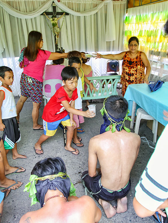 Boy offering water to one of the Magdarame devotees who relive Christ's passion by carrying heavy crosses and flagellating themselves in San Fernando, Pampanga, during the Maleldo 2019, Holy Week Philippines, photo by Ivan Kralj