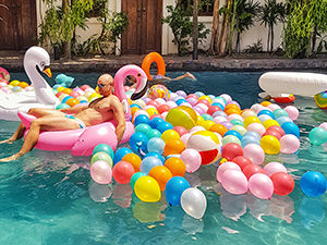 A guest is lying on a flamingo floatee in the swimming pool of Rambutan Resort in Siem Reap, Cambodia, filled out with various balloons, for Gay Pride party