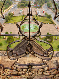 The view of Patuxai park through the Buddha-shaped grille at one of the towers of Patuxai, Vientiane, Laos, photo by Ivan Kralj