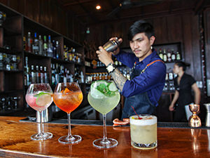 Trying cocktails at The Spirit House is one of the best things to do in Vientiane, Laos; a barman is shaking the best drinking line-up of the house, photo by Ivan Kralj