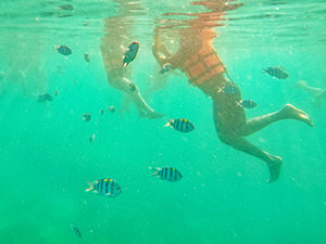 Underwater image of snorkelers in orange life jackets, swimming during the Coron Island Tour in Palawan, the Philippines, photo by Ivan Kralj