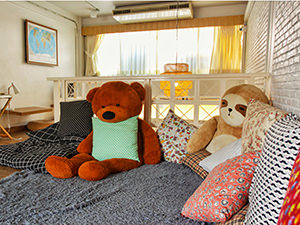 Common lounge room at Pakping Hostel, with pillows and big plush teddy bear and sloth toys, in Chiang Mai, Thailand, photo by Ivan Kralj