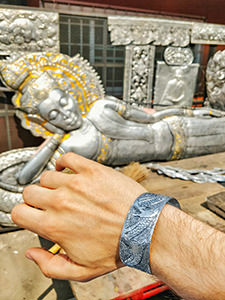 Dragon-decorated aluminum bracelet on the hand, made during the Backstreet Academy workshop in the learning center for the silverware art in Wat Sri Suphan, the Silver Temple of Chiang Mai, Thailand, photo by Ivan Kralj