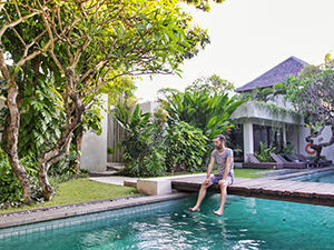 Pipeaway blogger Ivan Kralj sitting on the wooden walkway over the central swimming pool in The Amala resort, one of the best hotels in Bali, Indonesia, photo by Mladen Koncar