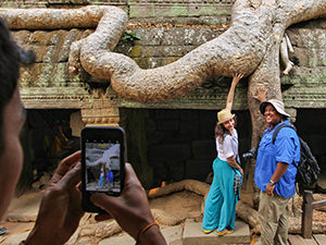 Tourists touching the tree in Ta Prohm temple, resembling a human bottom, for a photo, Angkor, Cambodia, photo by Ivan Kralj