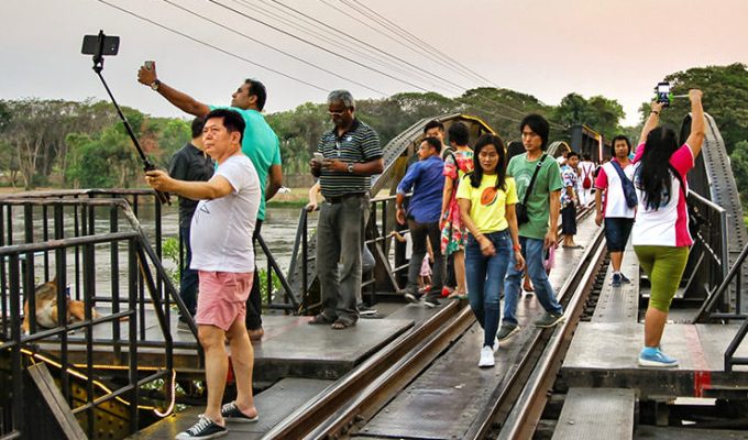 Tourists taking selfies on the River on the Bridge Kwai, a part of the Death Railway from the Second World War, in Kanchanaburi, Thailand, photo by Ivan Kralj