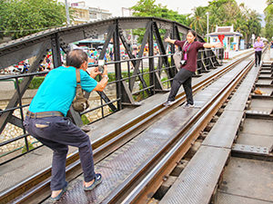 Woman posing for a photo while balancing on one foot on the train tracks of the Death Railway on the Bridge on the River Kwai, in Kanchanburi, Thailand, photo by Ivan Kralj