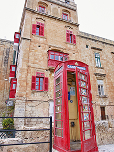 The red phonebox in front of the building with red windows in Valletta, the capital city of Malta, photo by Ivan Kralj