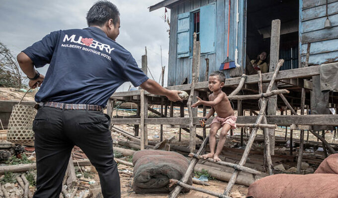 Mulberry hotel worker handing over a food parcel to a child in Cambodia, as part of the initiative Hotels Joining Hands directed to provide basic nutrition to people who lost their jobs due to coronavirus epidemic