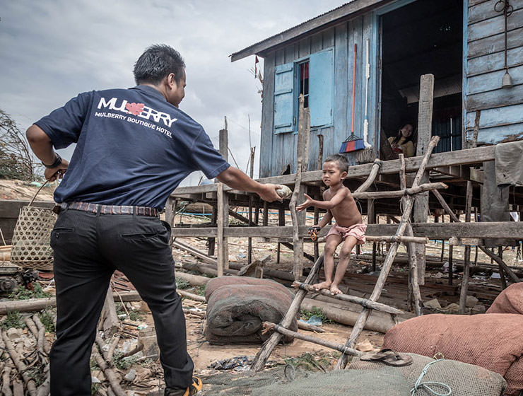 Mulberry hotel worker handing over a food parcel to a child in Cambodia, as part of the initiative Hotels Joining Hands directed to provide basic nutrition to people who lost their jobs due to coronavirus epidemic