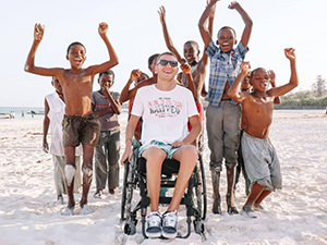 Slaven Škrobot, while traveling in a wheelchair throug Zanzibar, surrounded by the cheerful children on the beach