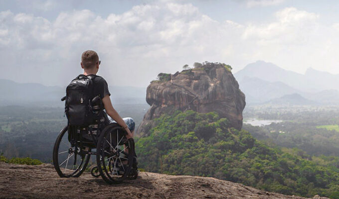 Slaven Škrobot, a traveler in a wheelchair, on the top of the Pidurangala rock with a view of Sigiriya rock in Sri Lanka