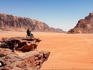 Slaven Škrobot traveling in a wheelchair through Wadi Rum desert in Jordan, enjoying the views from a rock