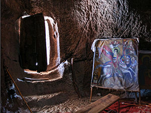 Entrance to a cave-like rock-hewn church Bet Denagel, with a painting of St. George killing a dragon. Lalibela. Ethiopia. Photo by Ivan Kralj