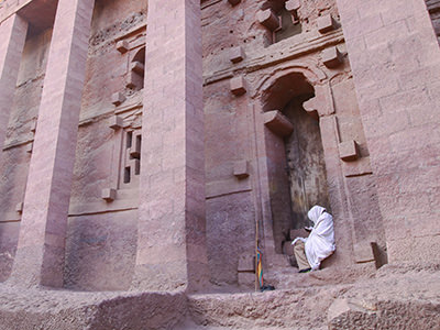 A pilgrim sitting outside of Bet Medhane, the largest Lalibela church carved out of rock, Ethiopia. Photo by Ivan Kralj