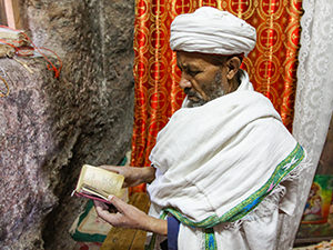 Priest in Bet Meskel, a tiny Lalibela church, with proportionally small Bible in his hands. Lalibela, Ethiopia. Photo by Ivan Kralj