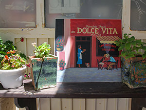 A painting of Dolce Vita patisserie and cafe displayed in front of it, Chalkio, Naxos, Greece, photo by Ivan Kralj