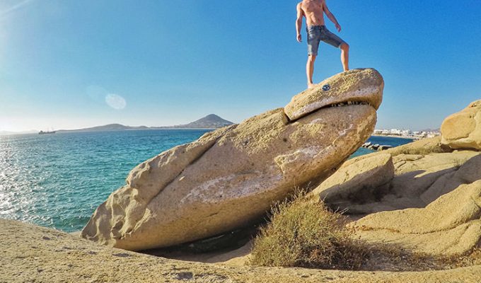 Travel blogger Ivan Kralj standing on a shark-shaped rock on Agia Anna Beach, one of the more unusual things to do in Naxos, Greece, photo by Ivan Kralj