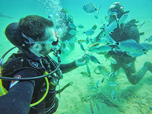 Travel blogger Ivan Kralj feeding the fish during the scuba diving with Blue Fin Divers at Agios Prokopios, Naxos, Greece, photo by Ivan Kralj