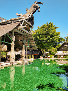 Swimming pool in front of the Kokok Pletok restaurant that has a rooster sculpture with snake tail on its roof, Hotel Tugu Lombok, Indonesia, photo by Ivan Kralj