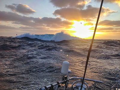 Wild sea and sun behind the clouds with birds flying around the sailboat during Bert terHart's trip around the world