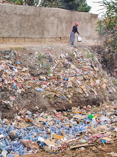 Woman throwing waste in the garbage-filled canal just outside of the city walls of Harar, Ethiopia, the town on the UNESCO World Heritage list, photo by Ivan Kralj