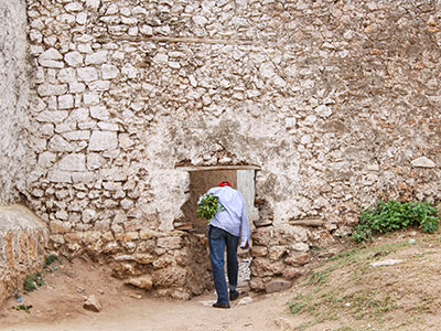 Man carrying chat plant passing through small hyena gate in Harar wall, Ethiopia, photo by Ivan Kralj
